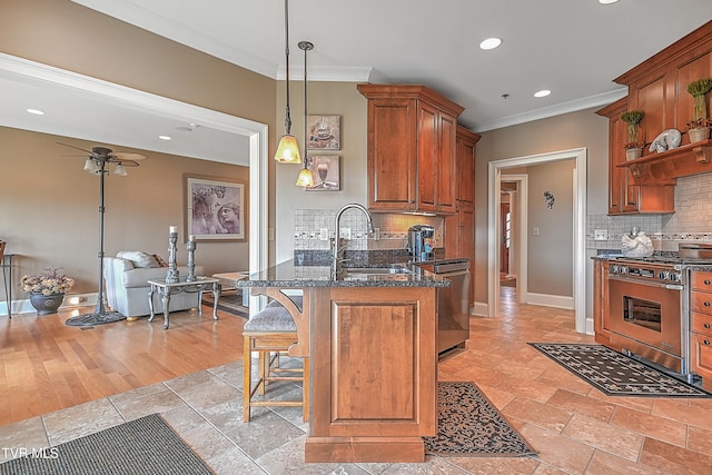 kitchen with sink, hanging light fixtures, stainless steel appliances, tasteful backsplash, and dark stone countertops