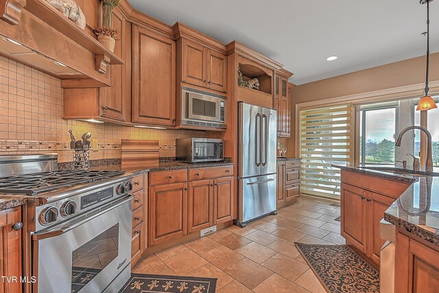 kitchen with backsplash, sink, decorative light fixtures, high quality appliances, and dark stone countertops