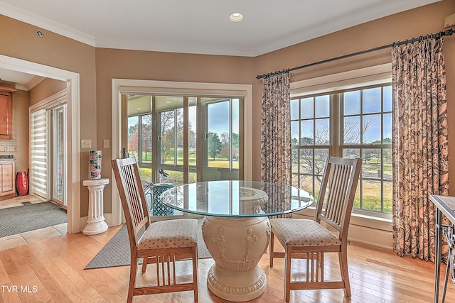 dining space with a healthy amount of sunlight, light wood-type flooring, and crown molding