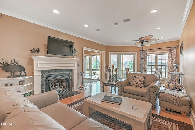 living room with hardwood / wood-style floors, ceiling fan, ornamental molding, and a high end fireplace