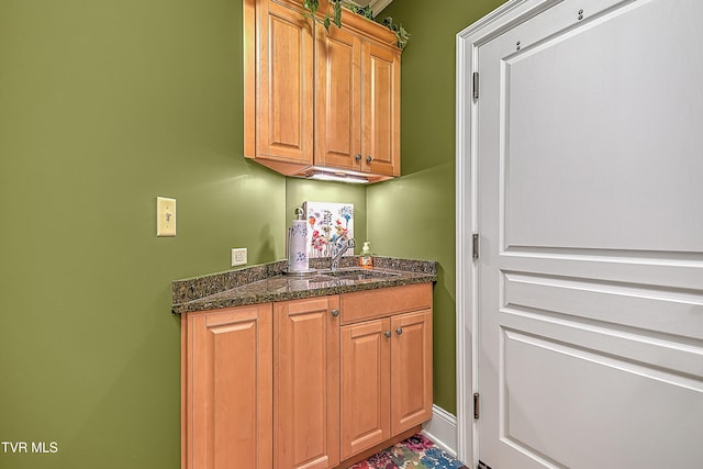 interior space featuring sink and dark stone counters