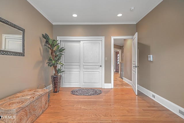 hall with light hardwood / wood-style floors and ornamental molding