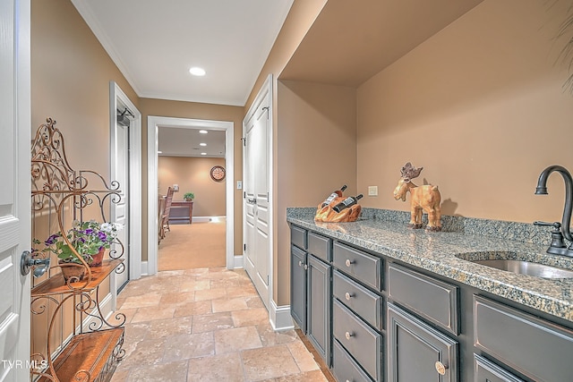 kitchen featuring gray cabinets, crown molding, dark stone counters, and sink