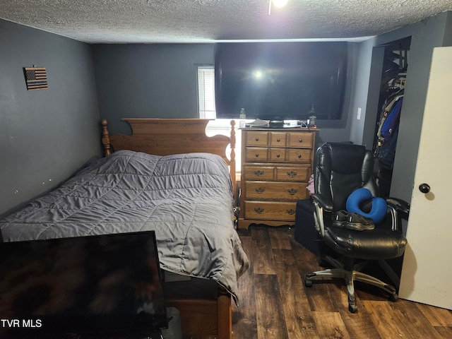 bedroom with dark hardwood / wood-style floors and a textured ceiling