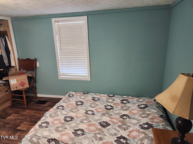 bedroom featuring dark hardwood / wood-style flooring and a textured ceiling