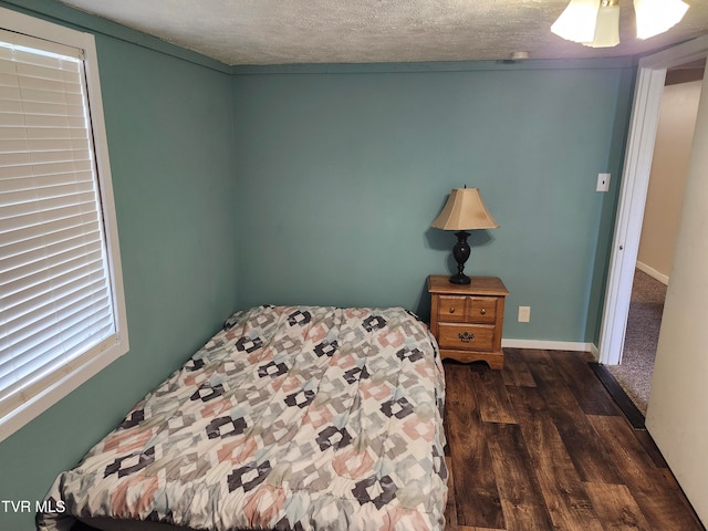 bedroom with ceiling fan, dark wood-type flooring, and a textured ceiling