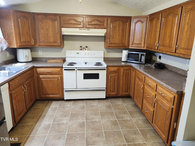 kitchen featuring a textured ceiling, lofted ceiling, sink, and white appliances