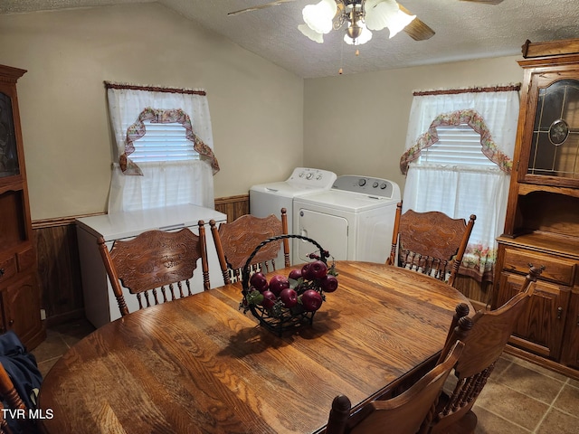 tiled dining area featuring a textured ceiling, wooden walls, washer and clothes dryer, and lofted ceiling