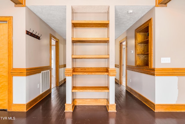 stairs featuring built in features, wood-type flooring, and a textured ceiling