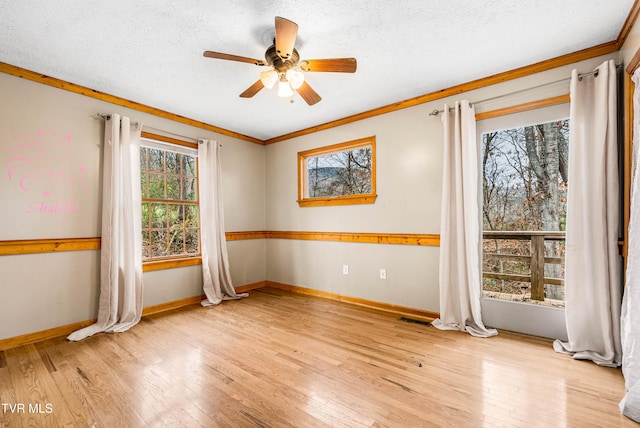 empty room with ceiling fan, light hardwood / wood-style floors, a textured ceiling, and ornamental molding