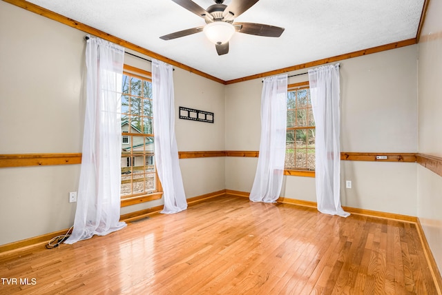 unfurnished room featuring light wood-type flooring, a wealth of natural light, crown molding, and ceiling fan