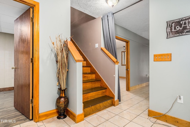 staircase with tile patterned floors and a textured ceiling