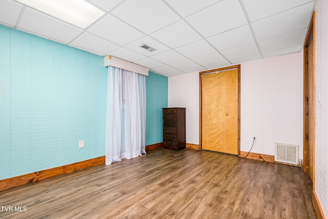 spare room featuring a paneled ceiling and wood-type flooring