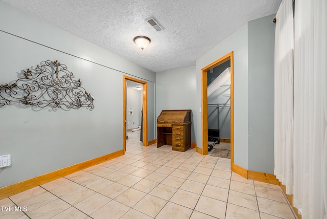 unfurnished room with light tile patterned flooring and a textured ceiling