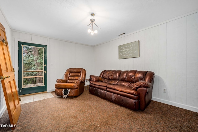 carpeted living room featuring ornamental molding and an inviting chandelier