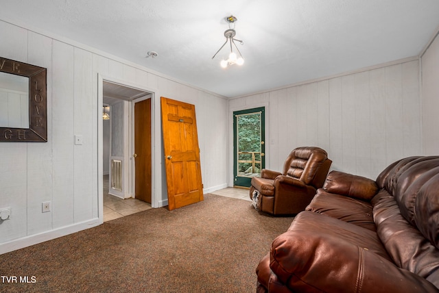 living room featuring wooden walls, light colored carpet, a textured ceiling, and a notable chandelier