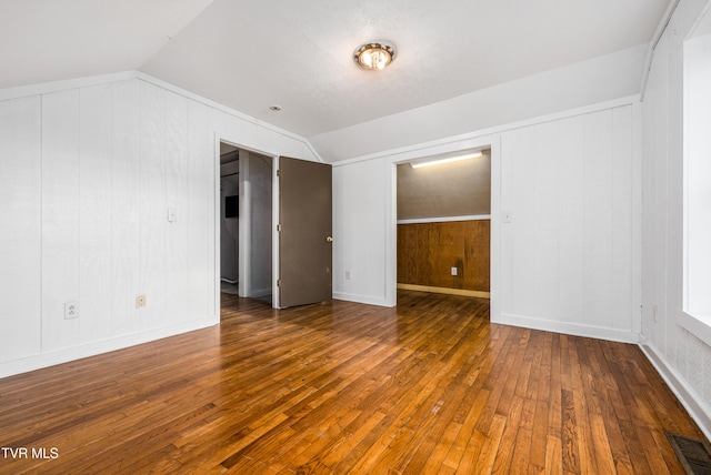 interior space featuring dark hardwood / wood-style floors, wood walls, and lofted ceiling