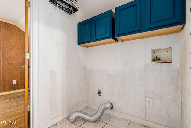 laundry room featuring cabinets, hookup for an electric dryer, wood walls, hookup for a washing machine, and light tile patterned floors