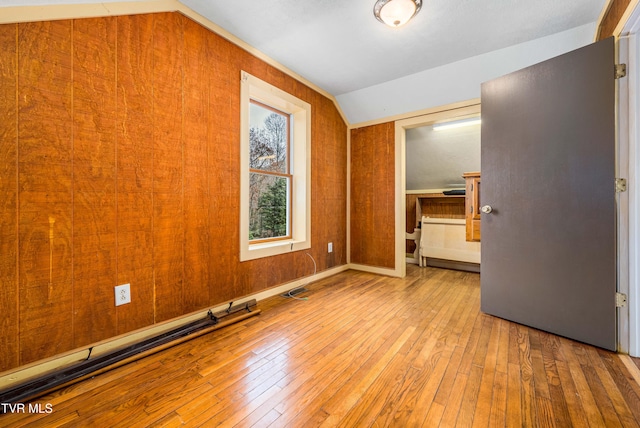 interior space with wooden walls, light hardwood / wood-style floors, and vaulted ceiling