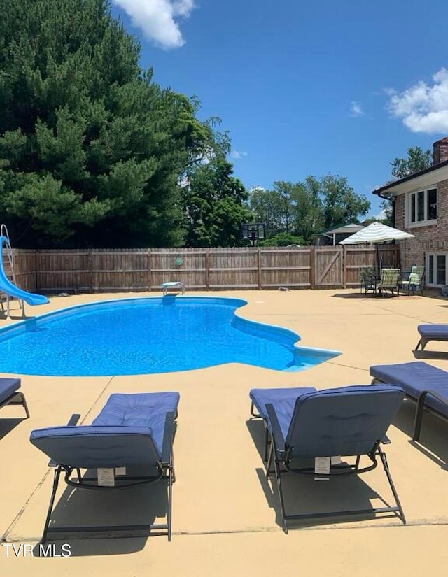 view of pool with a diving board, a patio area, and a water slide