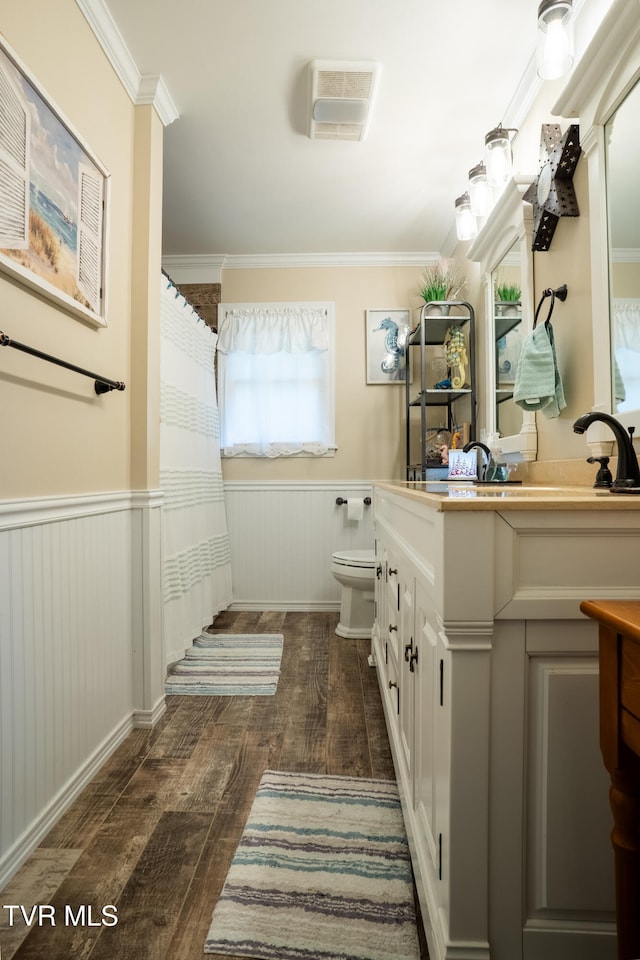 bathroom featuring toilet, vanity, wood-type flooring, and ornamental molding