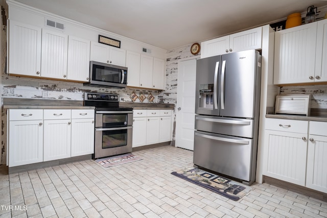 kitchen featuring appliances with stainless steel finishes, backsplash, and white cabinetry