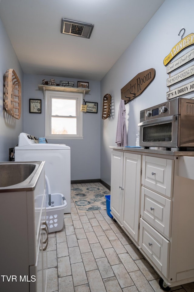 clothes washing area with cabinets and independent washer and dryer