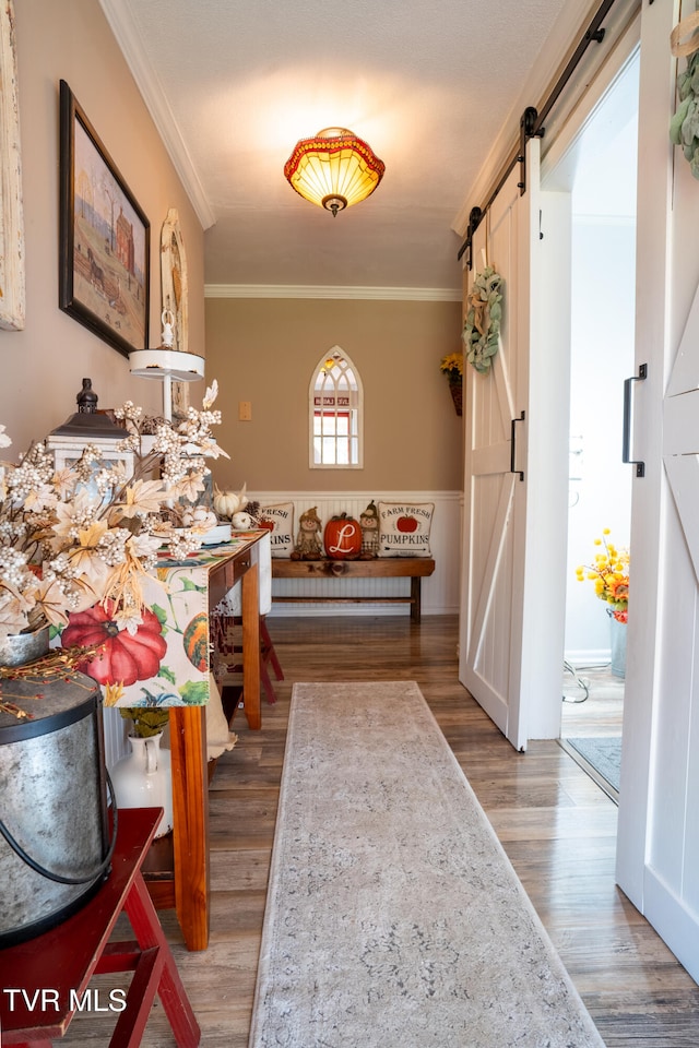 corridor with ornamental molding, a barn door, and dark wood-type flooring