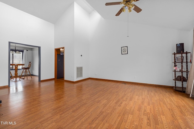 living room with ceiling fan with notable chandelier, light wood-type flooring, and high vaulted ceiling