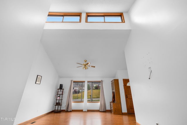 unfurnished living room with ceiling fan, high vaulted ceiling, and light hardwood / wood-style flooring