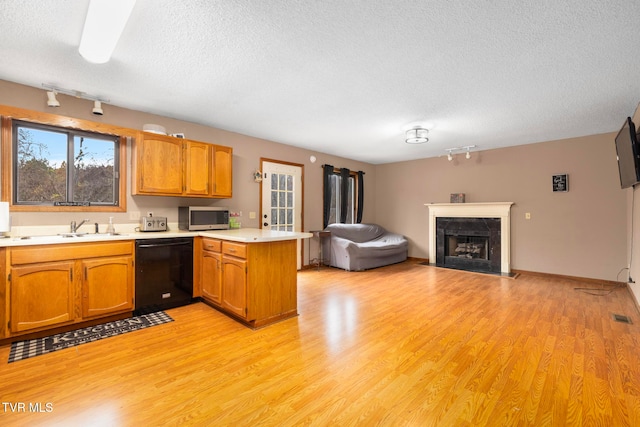 kitchen featuring kitchen peninsula, a textured ceiling, sink, black dishwasher, and light hardwood / wood-style floors