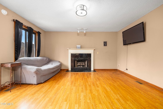 unfurnished living room featuring a textured ceiling, hardwood / wood-style flooring, and a premium fireplace