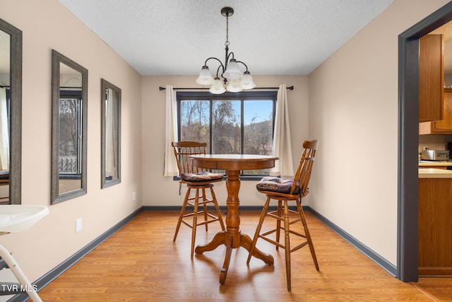 dining room featuring a textured ceiling, light wood-type flooring, and an inviting chandelier