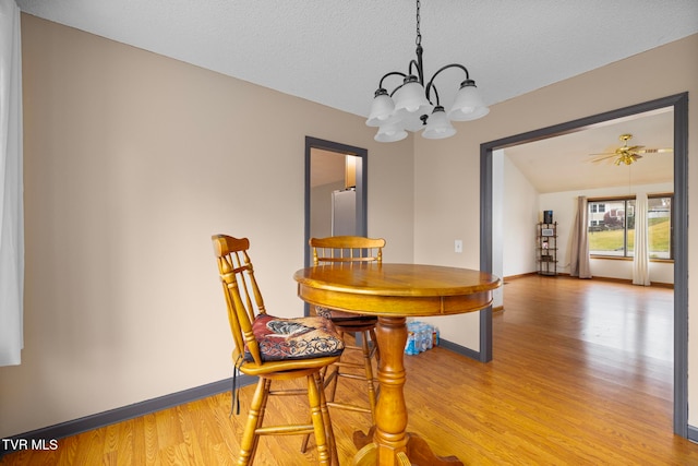 dining area featuring ceiling fan with notable chandelier, light hardwood / wood-style floors, and a textured ceiling