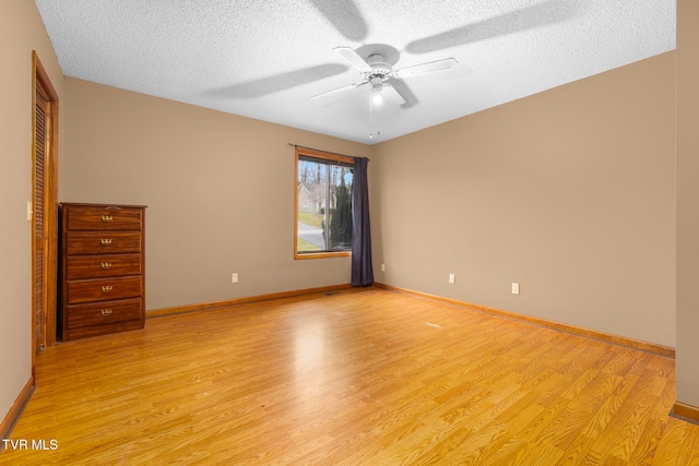 unfurnished room with ceiling fan, light hardwood / wood-style flooring, and a textured ceiling