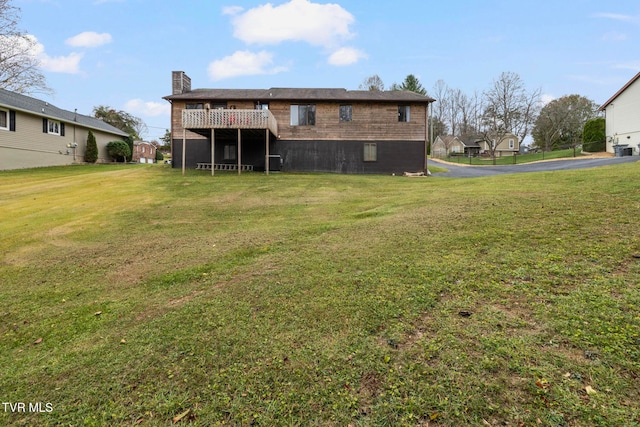 rear view of house with a yard and a wooden deck