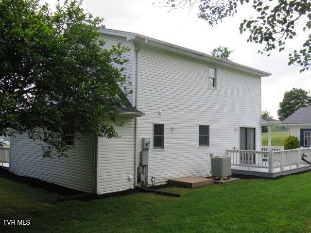 back of house featuring central AC, a lawn, and a wooden deck