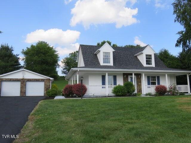 view of front of property with a front yard, a porch, a garage, and an outdoor structure