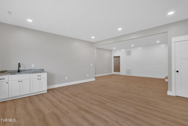 unfurnished living room featuring light wood-type flooring and sink