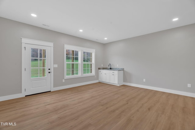 unfurnished living room with light hardwood / wood-style floors and sink