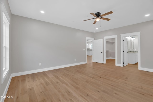 unfurnished bedroom with a walk in closet, ensuite bath, ceiling fan, light hardwood / wood-style floors, and a closet