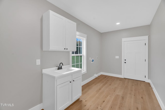 laundry area with cabinets, washer hookup, light wood-type flooring, and sink