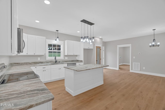 kitchen featuring white cabinets, a kitchen island, light hardwood / wood-style floors, and decorative light fixtures