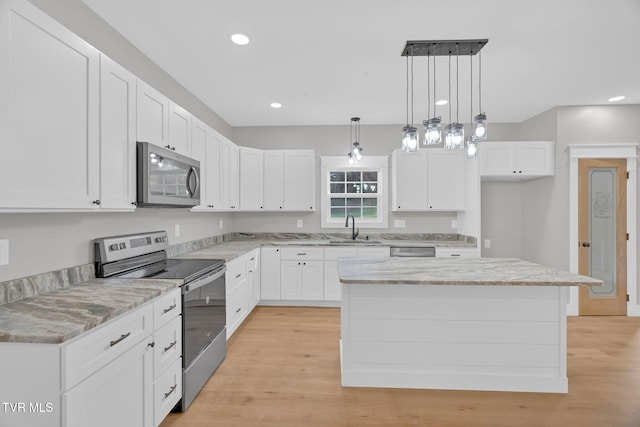 kitchen with white cabinets, appliances with stainless steel finishes, a center island, and decorative light fixtures