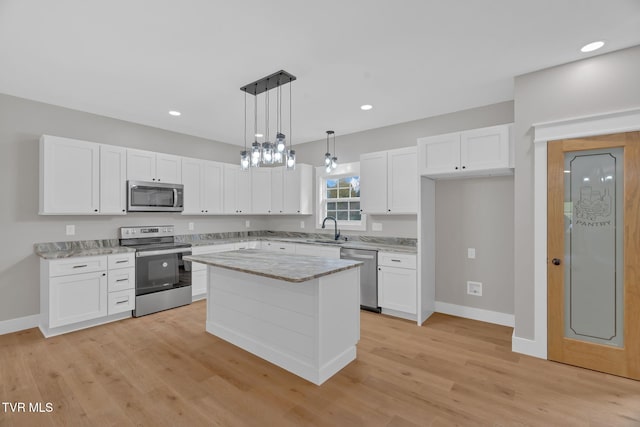 kitchen featuring a center island, white cabinets, decorative light fixtures, and appliances with stainless steel finishes