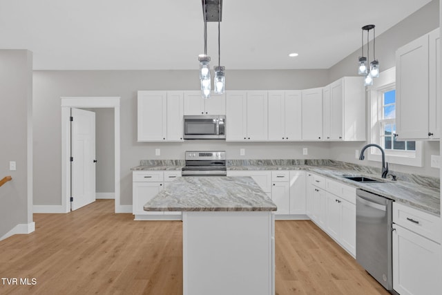 kitchen featuring appliances with stainless steel finishes, sink, white cabinets, a kitchen island, and hanging light fixtures