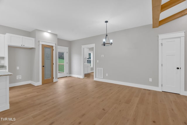 unfurnished living room featuring a notable chandelier, lofted ceiling with beams, and light hardwood / wood-style flooring