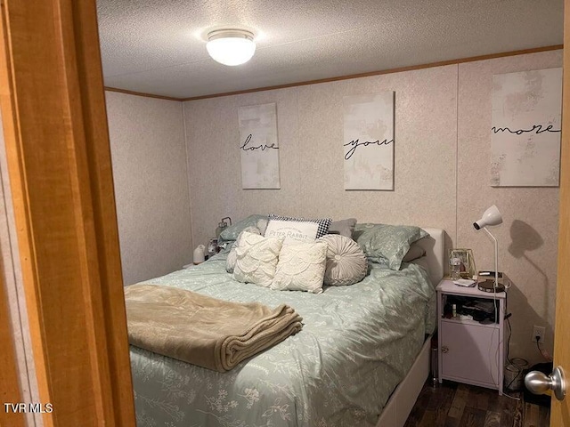 bedroom featuring dark hardwood / wood-style flooring, ornamental molding, and a textured ceiling