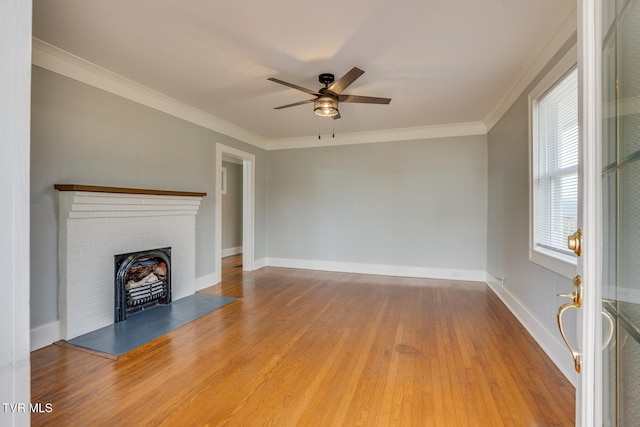 unfurnished living room featuring ceiling fan, wood-type flooring, crown molding, and a brick fireplace