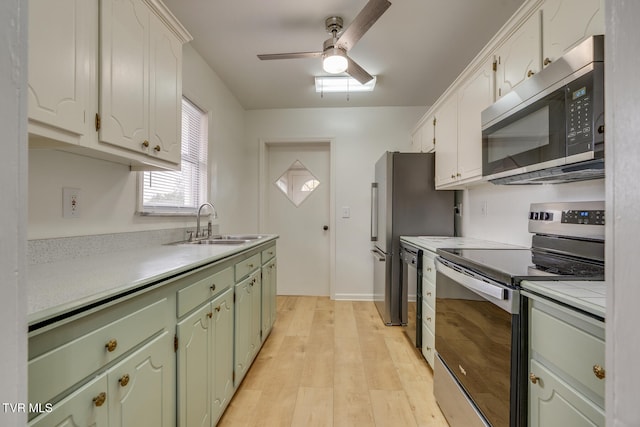 kitchen with appliances with stainless steel finishes, ceiling fan, sink, light hardwood / wood-style flooring, and white cabinetry